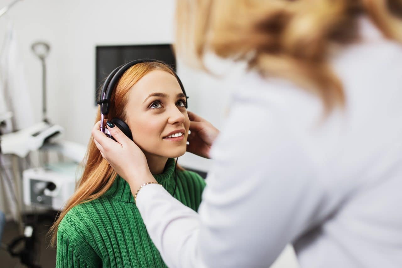 Young adult redhead woman at medical examination or checkup in otolaryngologist's office