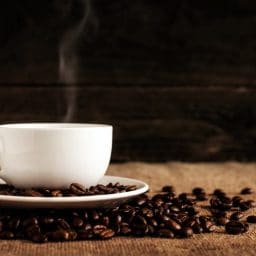 A cup of coffee surrounded by coffee beans