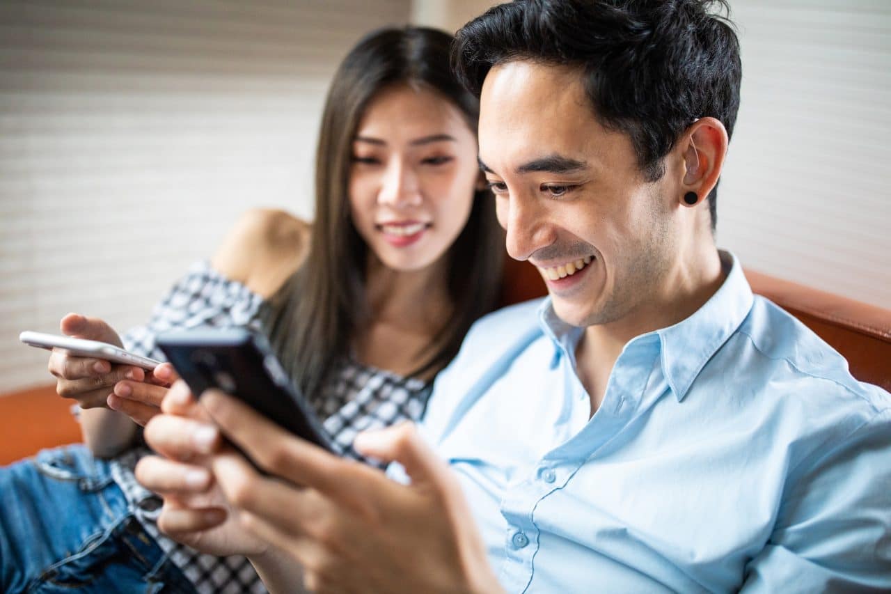 Younger man with a hearing aid looking at his smartphone.