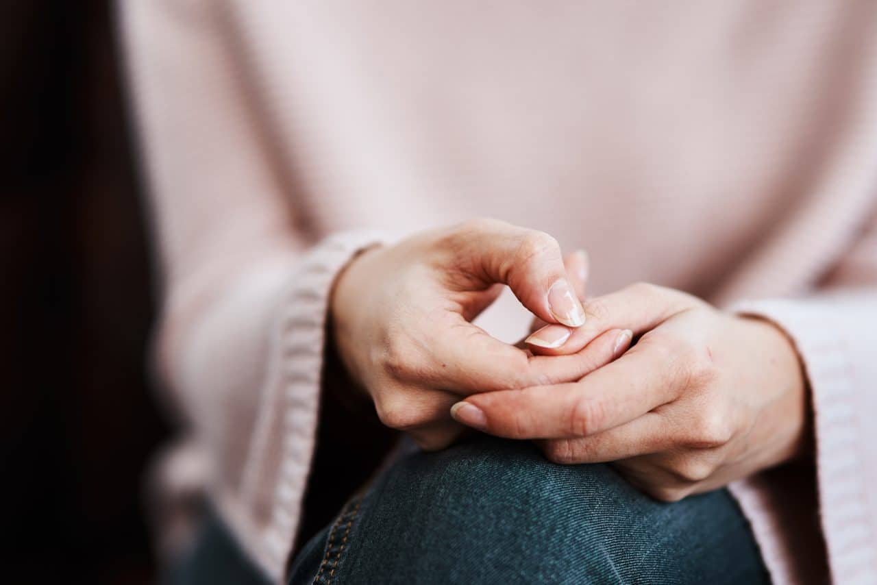 Woman anxiously clasping her hands.
