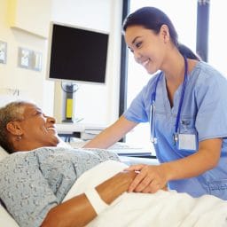A nurse checking in on an older woman in a hospital room.