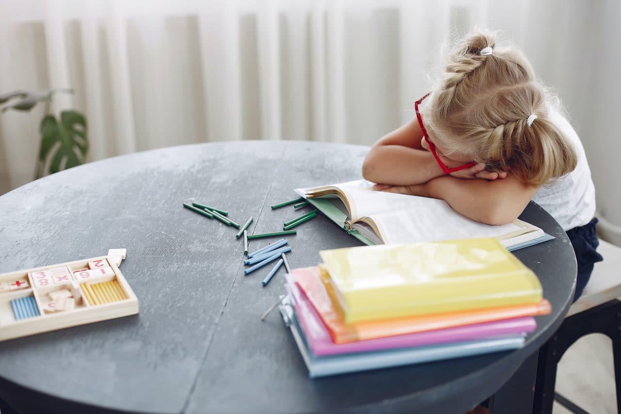 Tired little girl taking a nap at her desk.
