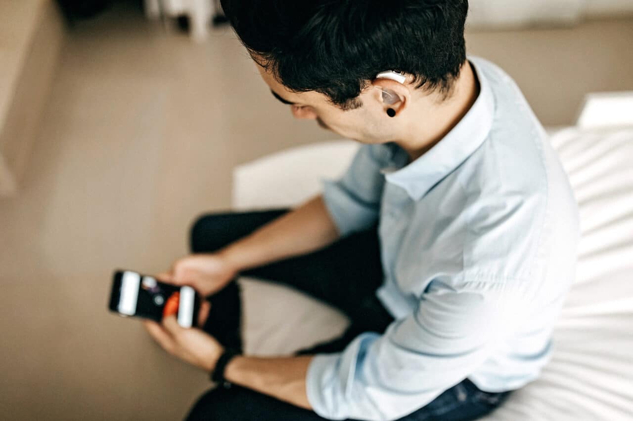 Young man with a hearing aid using his smartphone.