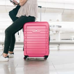 Close-up of a woman sitting on her luggage and waiting at the airport.