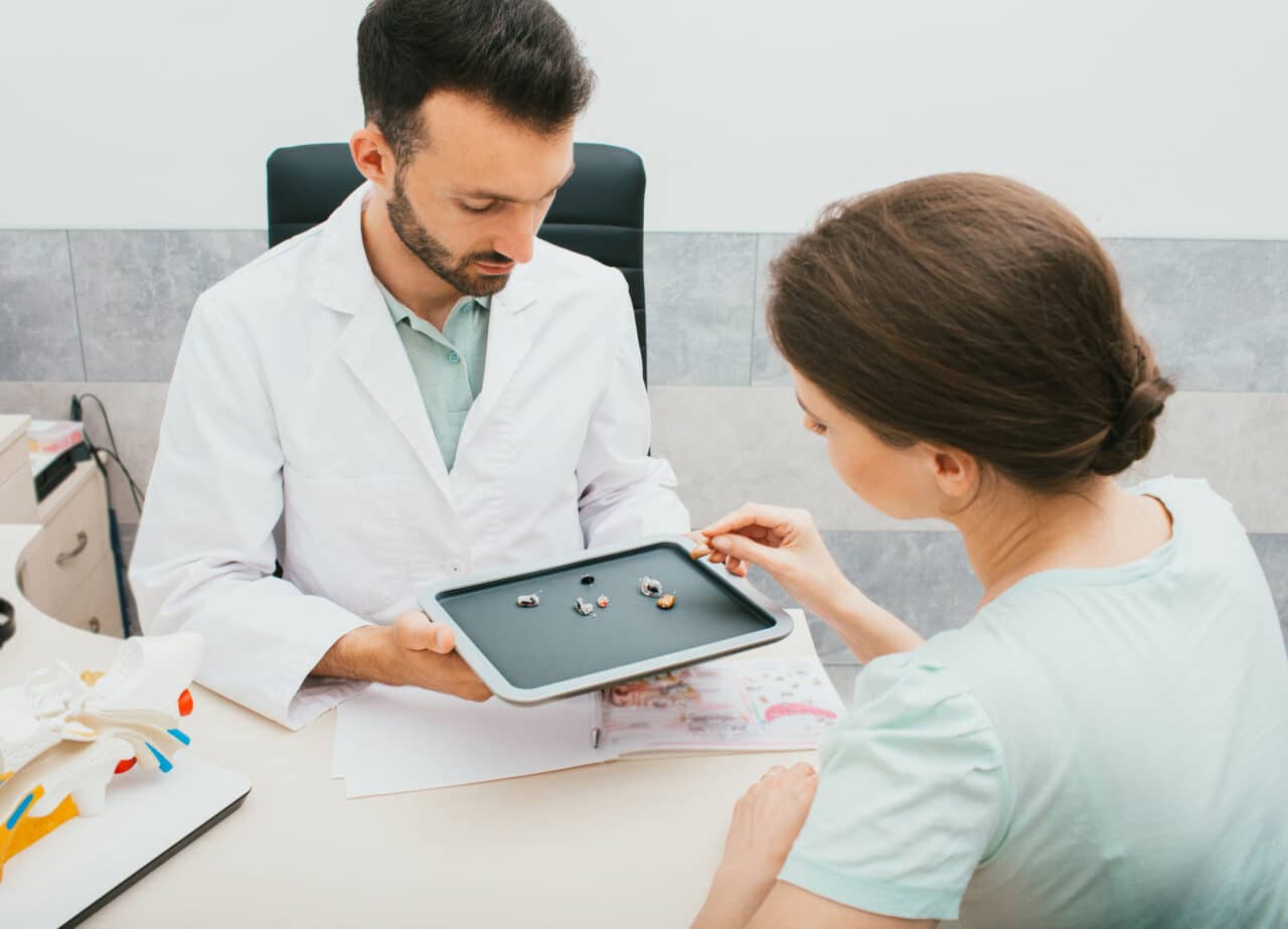 Audiologist helping a woman select a new pair of hearing aids.