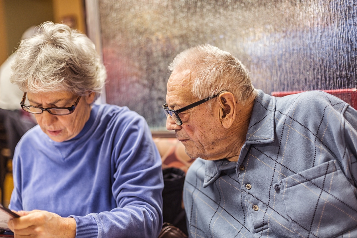 Man wearing a hearing at at a restaurant with his wife.