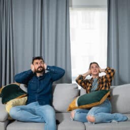 Two people cover their ears