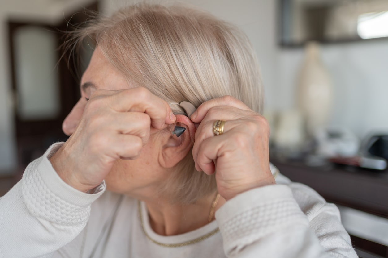 Woman adjusts her hearing aid