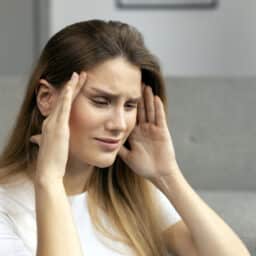 Woman with tinnitus, looking upset and holding her head