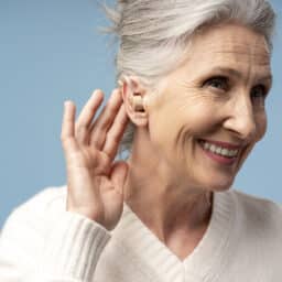 Happy senior woman showing off her hearing aid