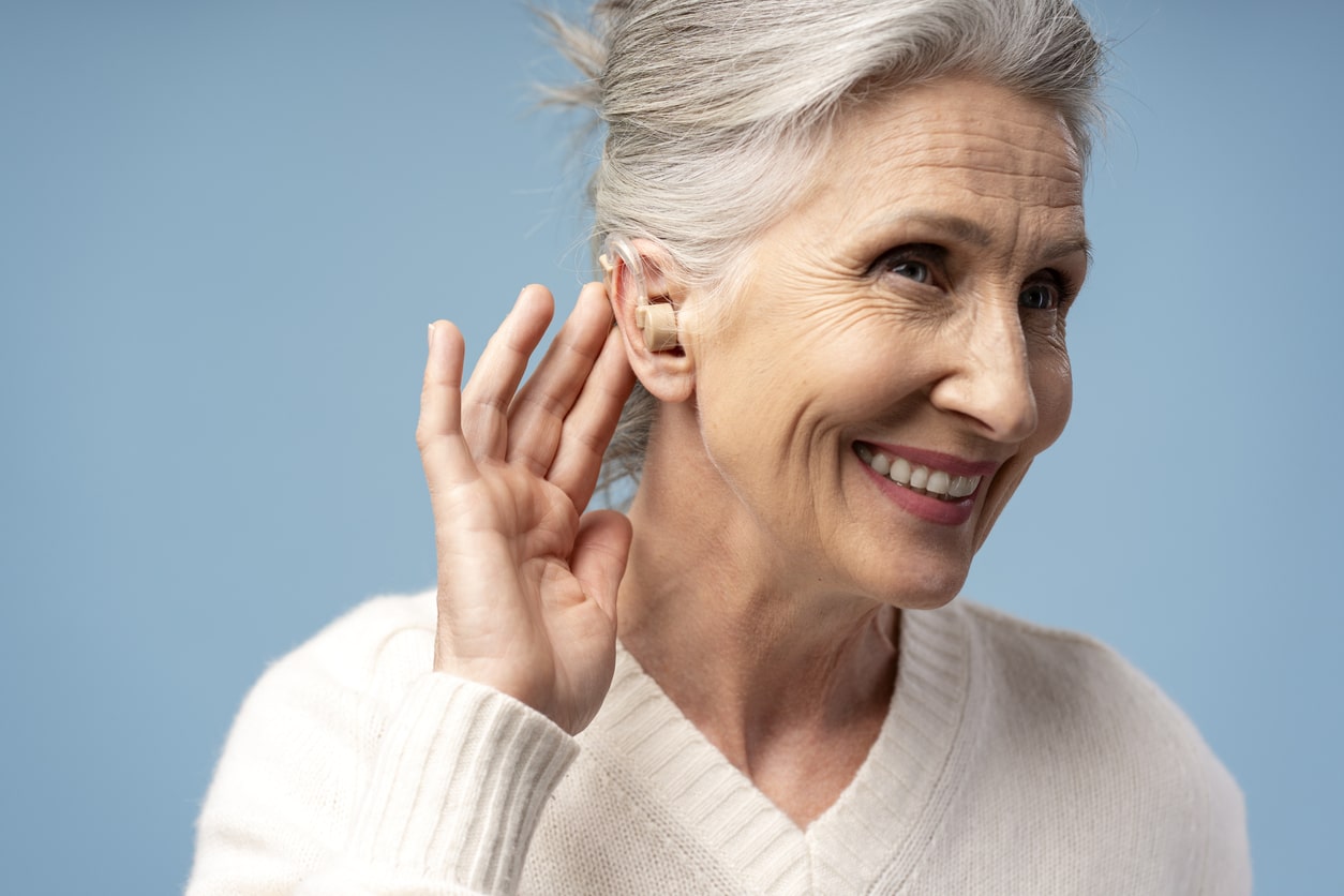 Happy senior woman showing off her hearing aid.