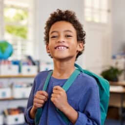 Smiling boy with a backpack at school.