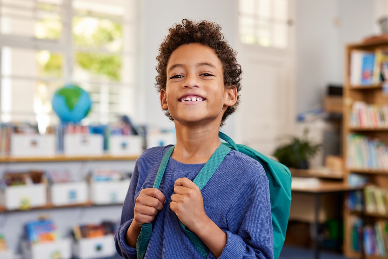 Smiling boy with a backpack at school.