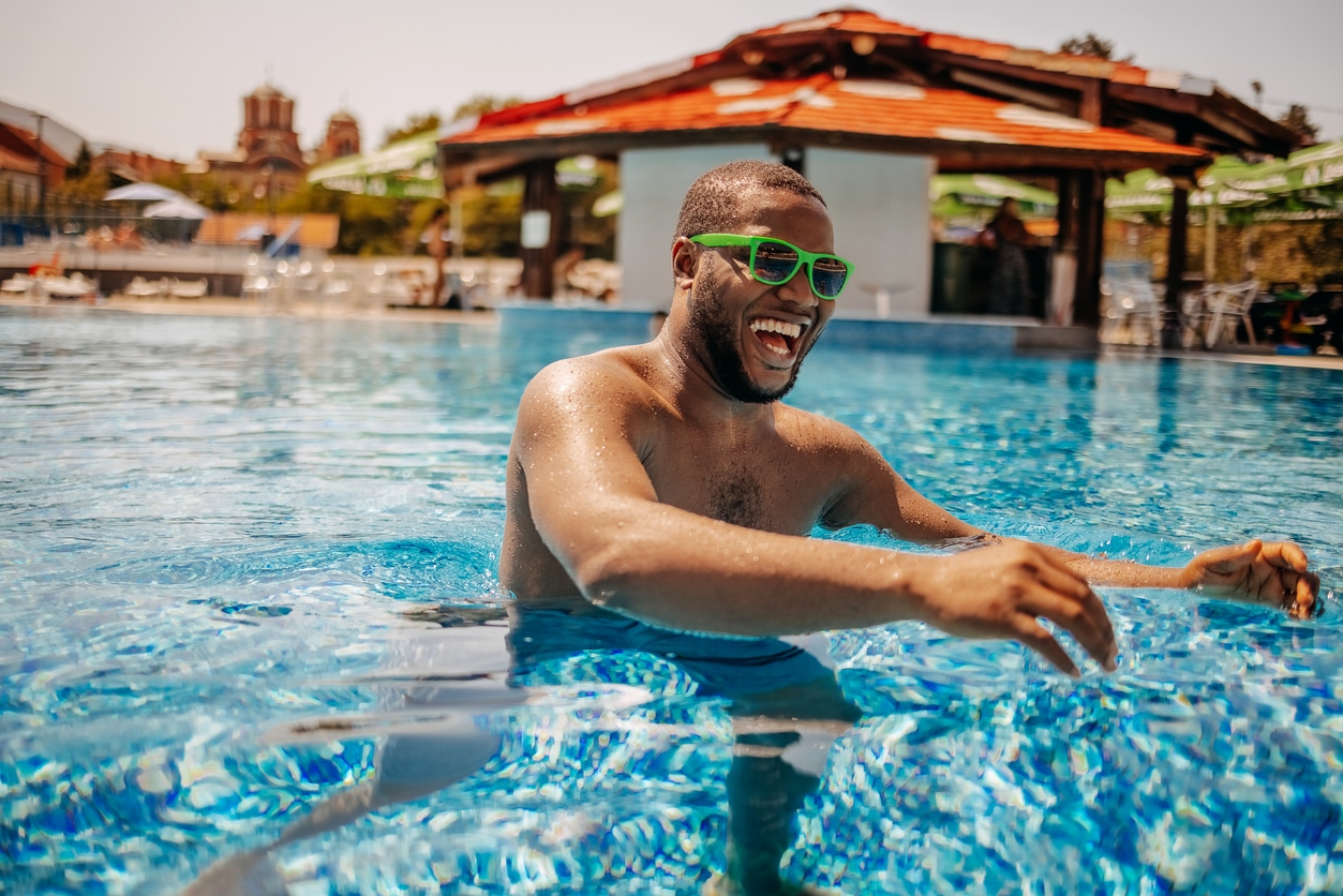  Young man having fun at public swimming pool in water on his vacation.