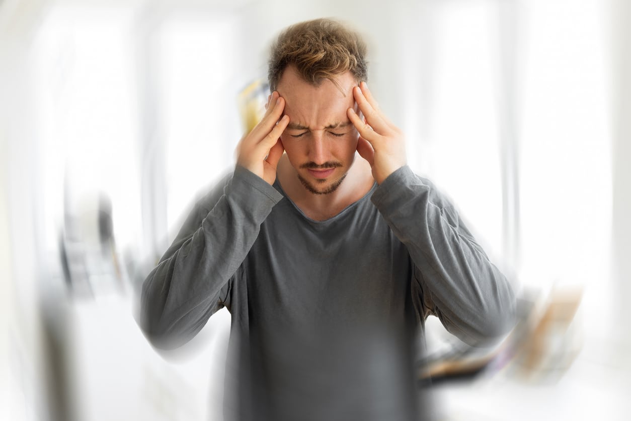 Man with tinnitus holding his head, blurred effect around him