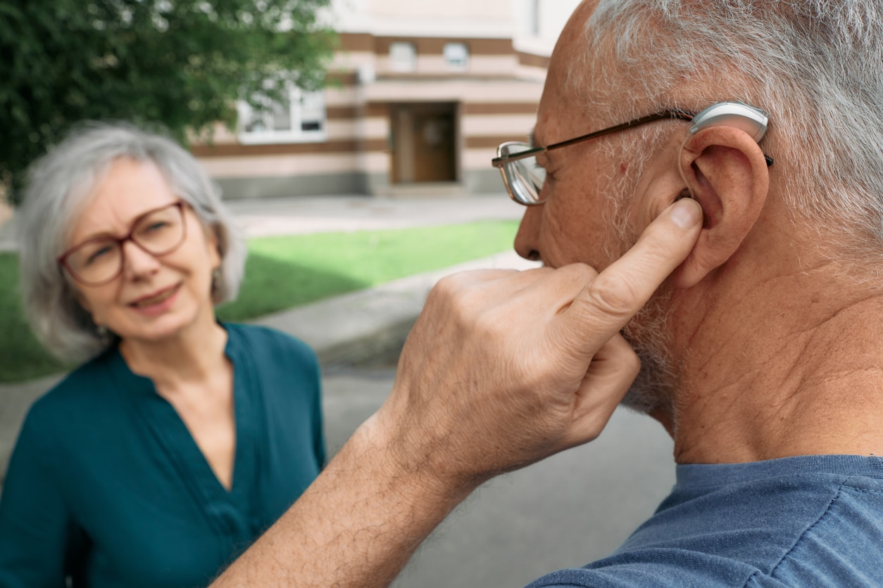 Senior man showing his friend his hearing aid