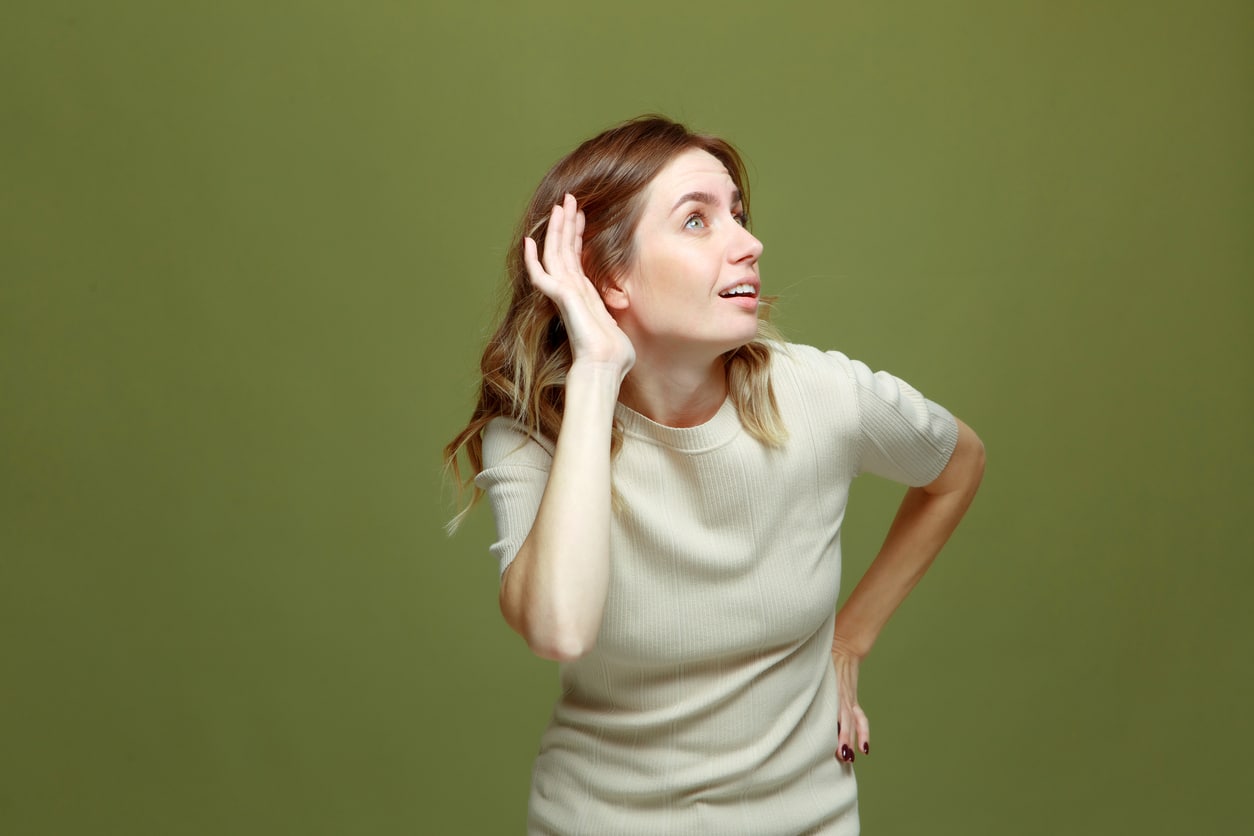 Young woman with her hand to her ear trying to hear