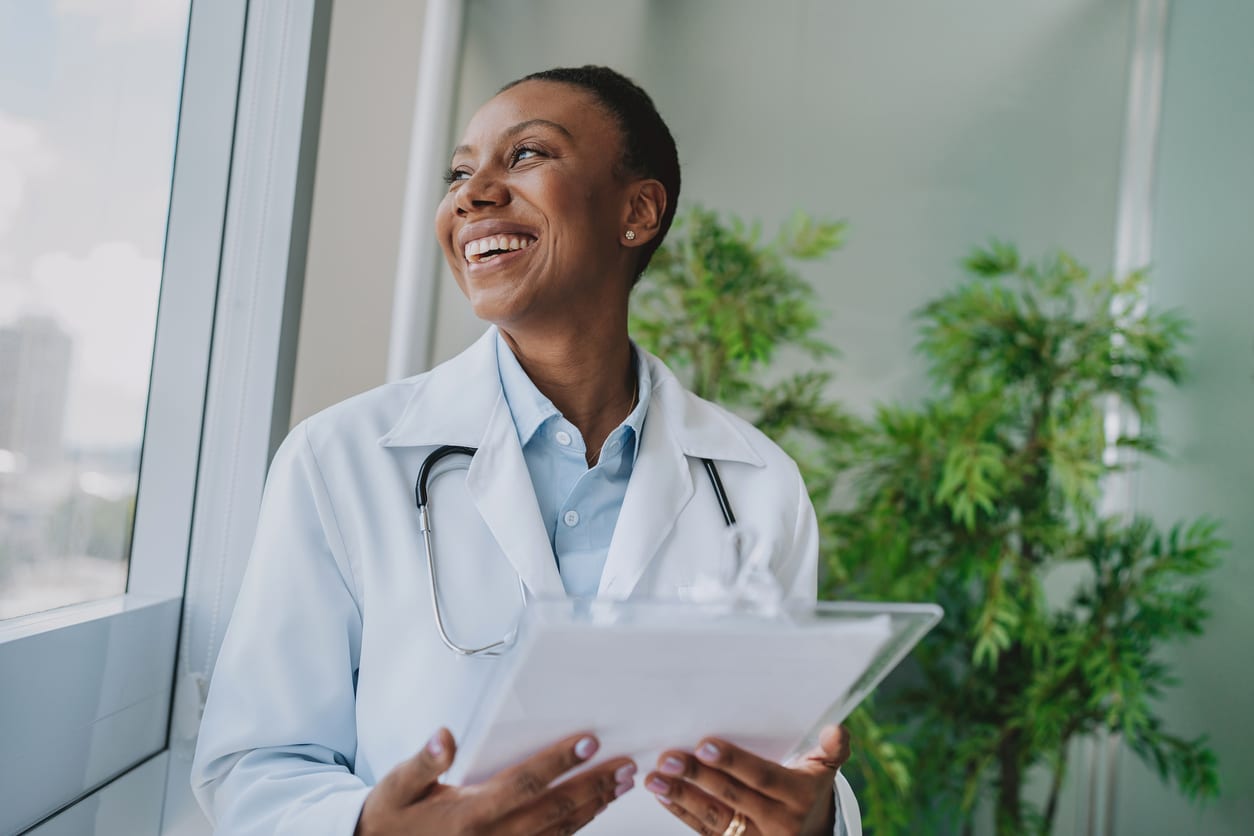 Smiling doctor looking out the window in her office. 