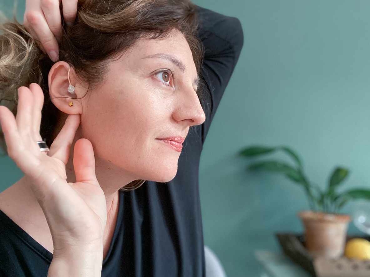 Smiling woman showing her properly placed hearing aid.
