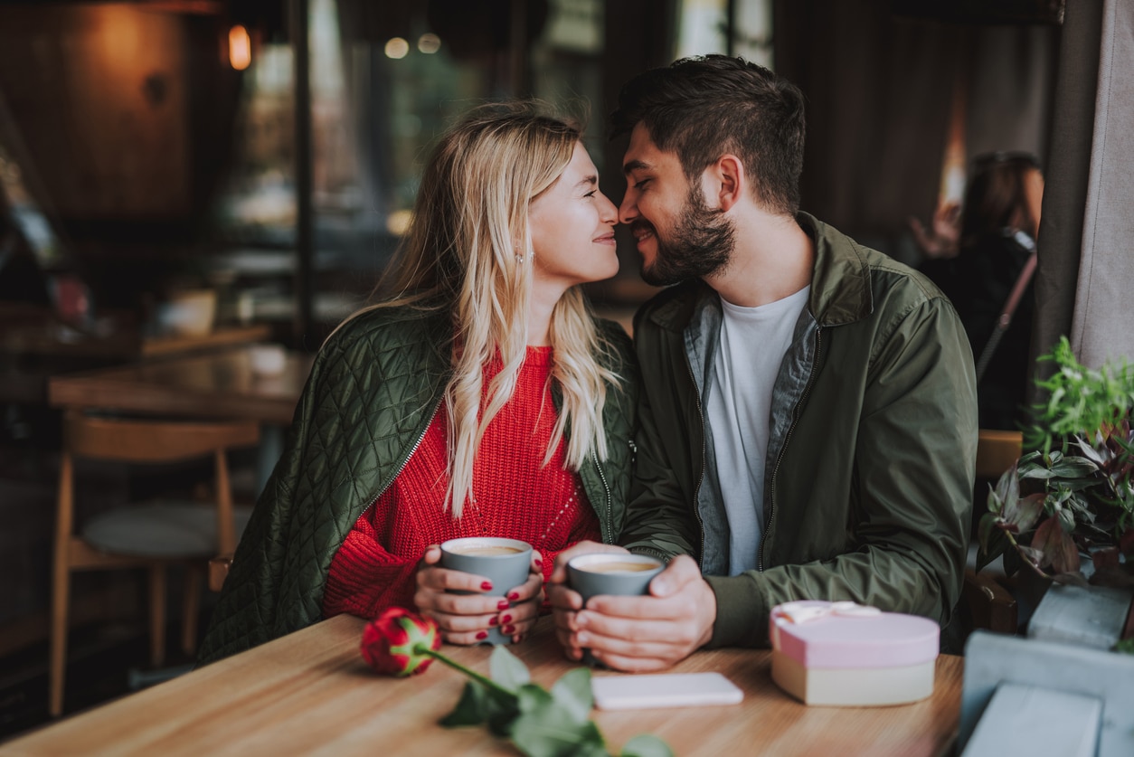 Young couple touching noses and smiling at cafe.