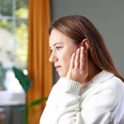 Woman holding her hand against her ear.