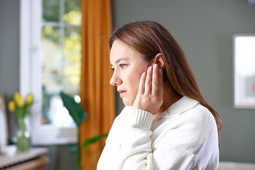 Woman holding her hand against her ear.