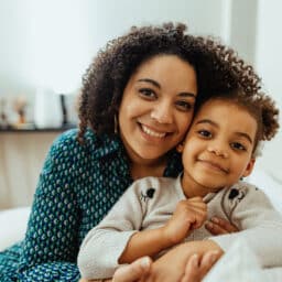 Mom hugging her child and smiling.