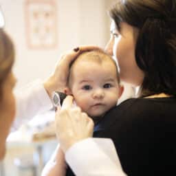 Mom holding her baby during an ear exam.