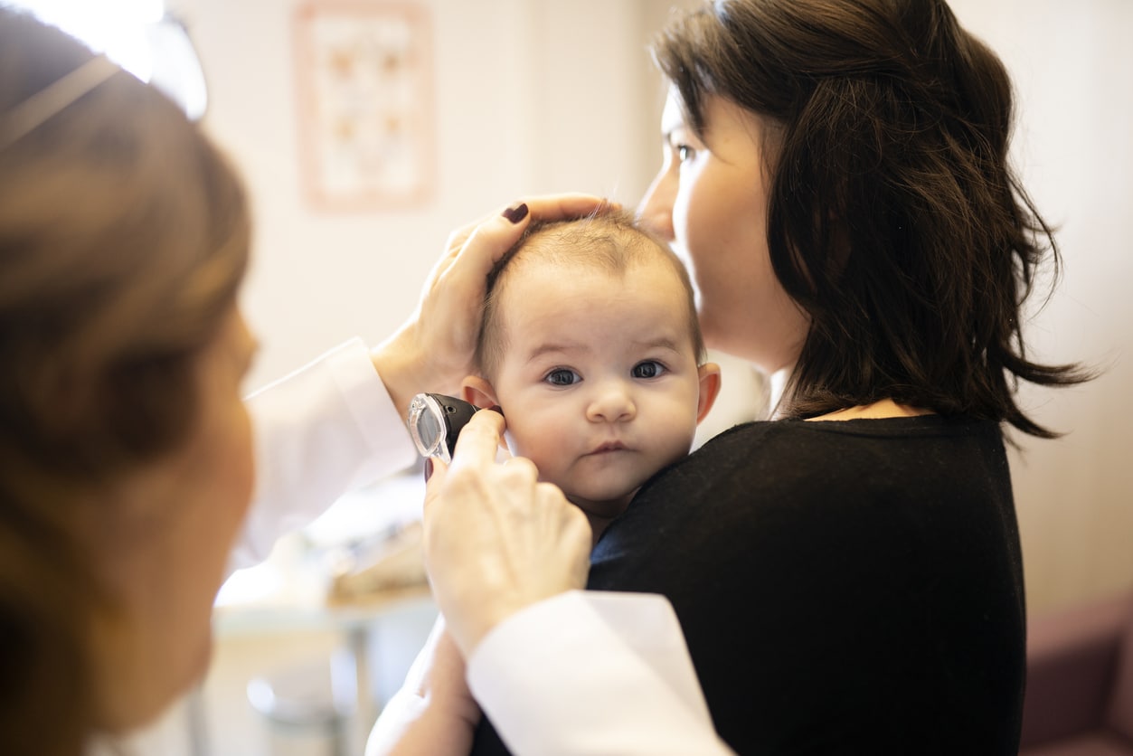 Mom holding her baby during an ear exam.