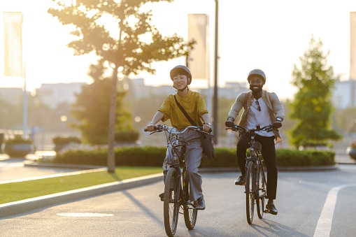 Two people enjoying a leisurely bike ride through the city. The sun shines brightly, casting a warm glow over the scene, and highlighting the joy of outdoor activities.