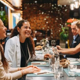 Group of friends laughing and enjoying dinner together at a restaurant, celebrating and having fun