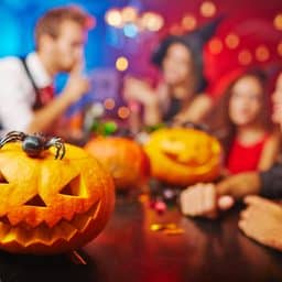 Jack-o-lanterns sitting on a table with out of focus people in the background.