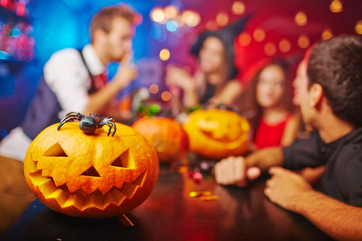 Jack-o-lanterns sitting on a table with out of focus people in the background.